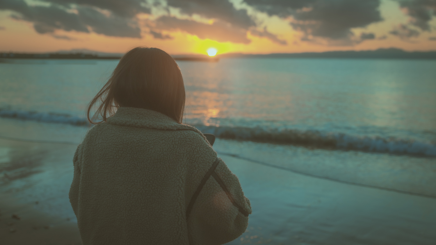 夕方に女性が冬の海を見つめている